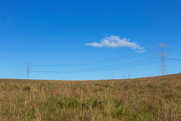 Electric power tower in the countryside, blue sky background.