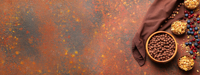 Tasty chocolate corn balls and crunchy granola with berries on color background with space for text