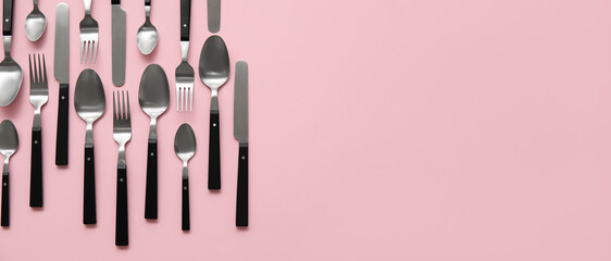 Many different cutlery on pink background with space for text