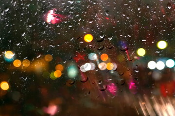  rainy  drops on window glass ,city blurred evening light on window with rain drops nature background