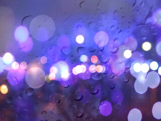  rainy  drops on window glass ,city blurred evening light on window with rain drops nature background