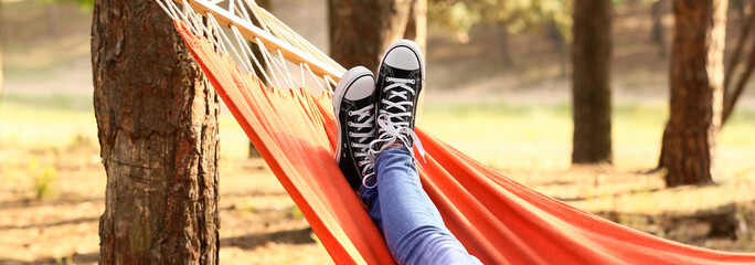 Legs of young woman relaxing in hammock outdoors - obrazy, fototapety, plakaty