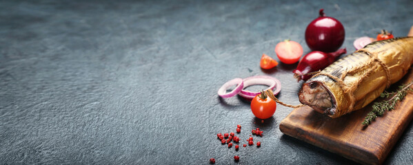 Board with tasty smoked mackerel fish and fresh vegetables on dark background with space for text, closeup