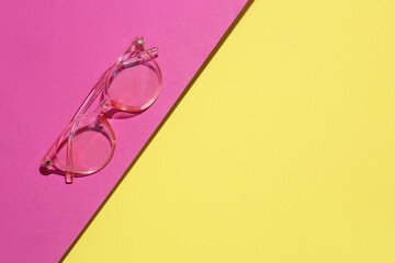 Pink eyeglasses on color background