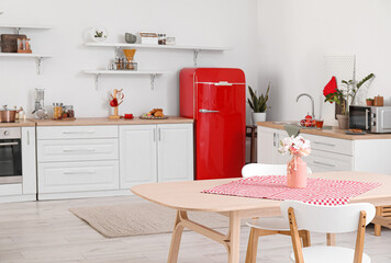 Pink vase with flowers on dining table in light kitchen