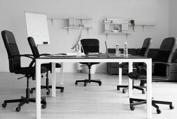 Big table with modern computers and bottles of water in conference room interior