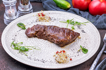 roast beef Steak machete on grey plate on dark stone table side view