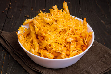 french fries on bowl with cheese on dark wooden table