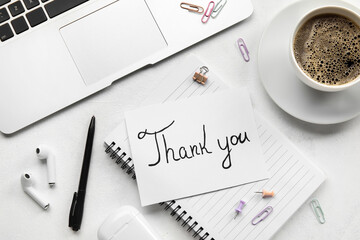 Card with text THANK YOU, earphones, laptop and cup of coffee on white background