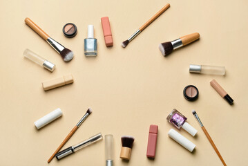 Frame made of makeup brushes and cosmetic products on beige background