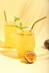 Glasses of delicious passion fruit juice on yellow background
