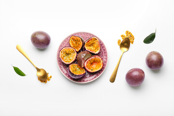 Plate with delicious cut passion fruits on white background