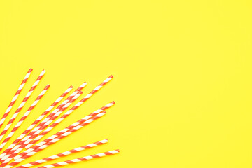 Stylish straws for drinks on yellow background