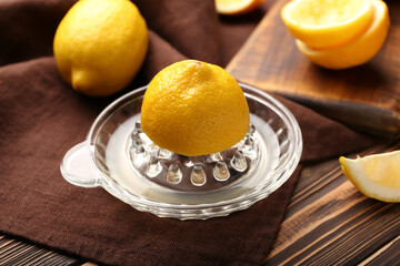 Juicer with ripe lemon on wooden background