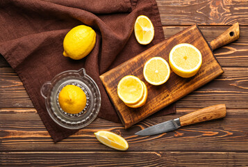 Composition with juicer and ripe lemons on wooden background
