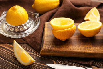 Board with cut ripe lemon on wooden background