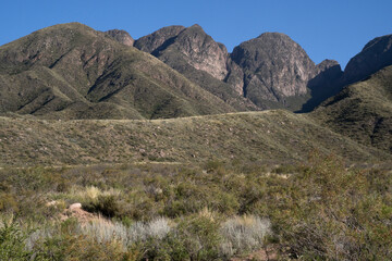 View of the green meadow and hills under a blue sky in a sunny summer day.	
