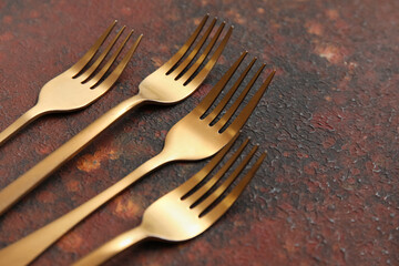 Golden forks on grunge background, closeup