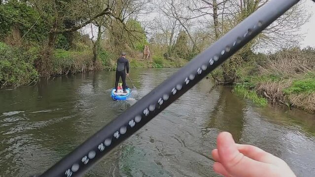 POV SUP Paddleboarder paddles upstream on narrow Irish country river