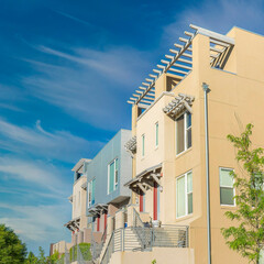 Square Whispy white clouds Fenced residential buildings with stairs to the verandas at Dayb