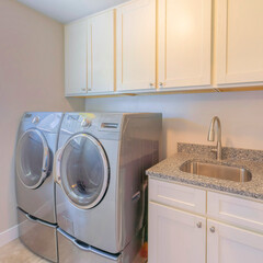 Square Laundry interior with front load laundry units and vanity sink