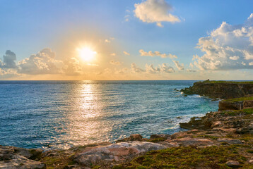 sunrise at punta sur beach in isla mujeres. spectacular sky with clouds and an impressive sun.