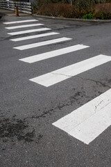 White stripes of a sidewalk on a cracked asphalt street
