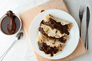 Tacos of mole with rice, placed on wood, in the background a piece of chicken - obrazy, fototapety, plakaty
