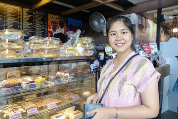 Young asian woman choosing sweet products at grocery supermarket shopping at pastry shop.