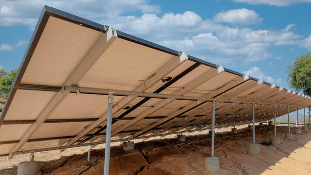 Panorama White puffy clouds Support structures of a solar panels with concrete foundation an