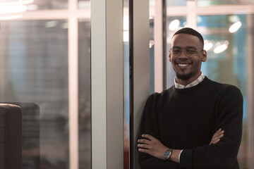  African American man looking at camera standing in office lobby hall. Multicultural company managers team portrait.