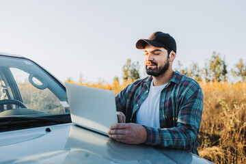Young latin farmer man on his pickup truck and working on his laptop. Agricultural concept. © padnob