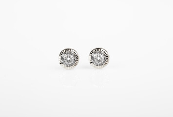 Round silver stud earrings with diamond on white background.