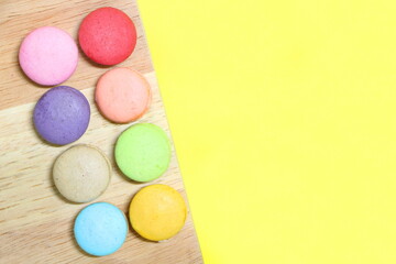 Fototapeta na wymiar Line of colorful fresh sweet cake macarons on wood, have yellow copy space for put text.