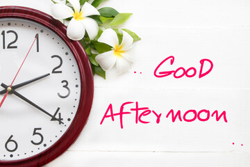 good afternoon message card handwriting with clock, flowers frangipani arrangement flat lay postcard style on background white 