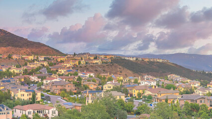 Obraz premium Panorama Puffy clouds at sunset Residential area in between the mountains against the colorful s