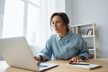 Interested concentrated focused smart gorgeous pensive curly businesswoman typing tax report read important information at screen using laptop in office. Modern Job Remote Work concept