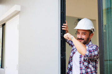 Man installing windows in  new house construction site. Hispanic Construction worker wearing protect gloves and hardhat helmet