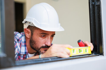 Man installing windows in  new house construction site. Hispanic Construction worker wearing...