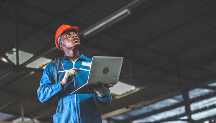 Black male electrician engineer working with laptop computer tool in his hands. Maintenance service...
