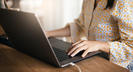 Focus on hand, young casual businesswoman using computer laptop working online on wooden table at home, Close up view