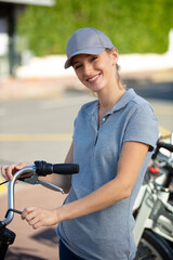Naklejka premium young happy positive woman master is repairing bicycle in workshop