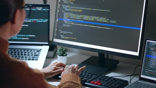Young Asian woman, developer programmer, software engineer, IT support, wearing glasses working hard at night overtime on computer to check coding in bugging system. Back view