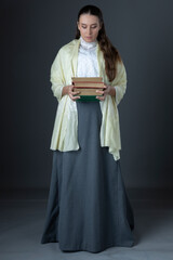 A Victorian or Edwardian woman with long hair standing and holding books