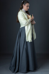 A Victorian or Edwardian woman with long hair standing and holding books