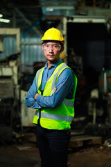 Confident Asian man worker look at camera thumps up. Metal machine in heavy Industry Manufacturing. Asian male factory worker wearing safety hard hat helmet