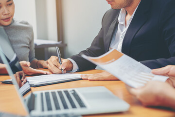 Businessman puts signature on contract at business meeting and passing money after negotiations with business partners. Selected focus	