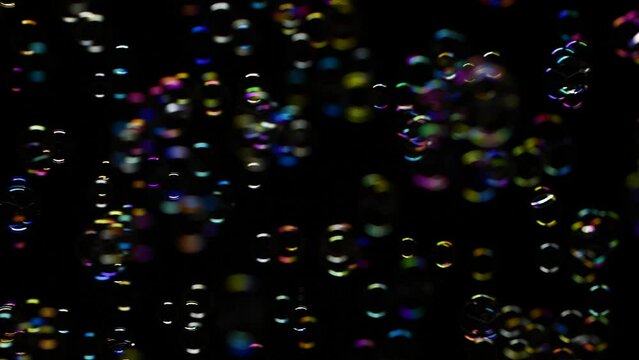 Slow motion of vertical soap water bubbles texture flying over black background
