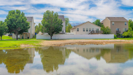 Fototapeta na wymiar Panorama Whispy white clouds Shallow lake in a residential community at Utah valley