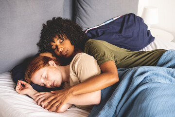 Young lesbian couple lying and sleeping in their bed, LGBT lifestyle - obrazy, fototapety, plakaty